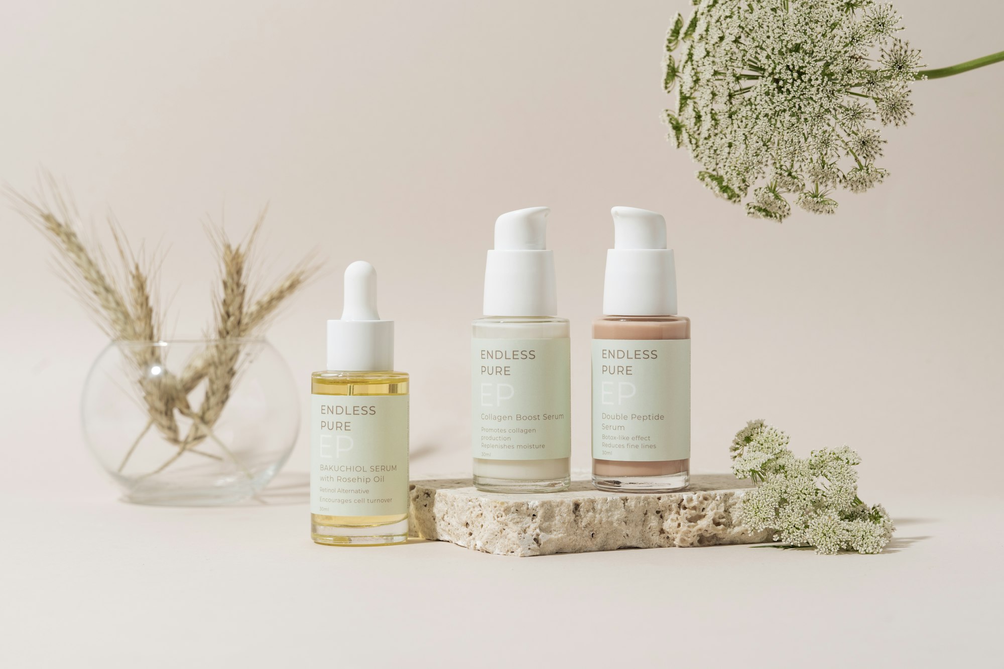 Flaskor med serum och hudvård bland torkade blommor